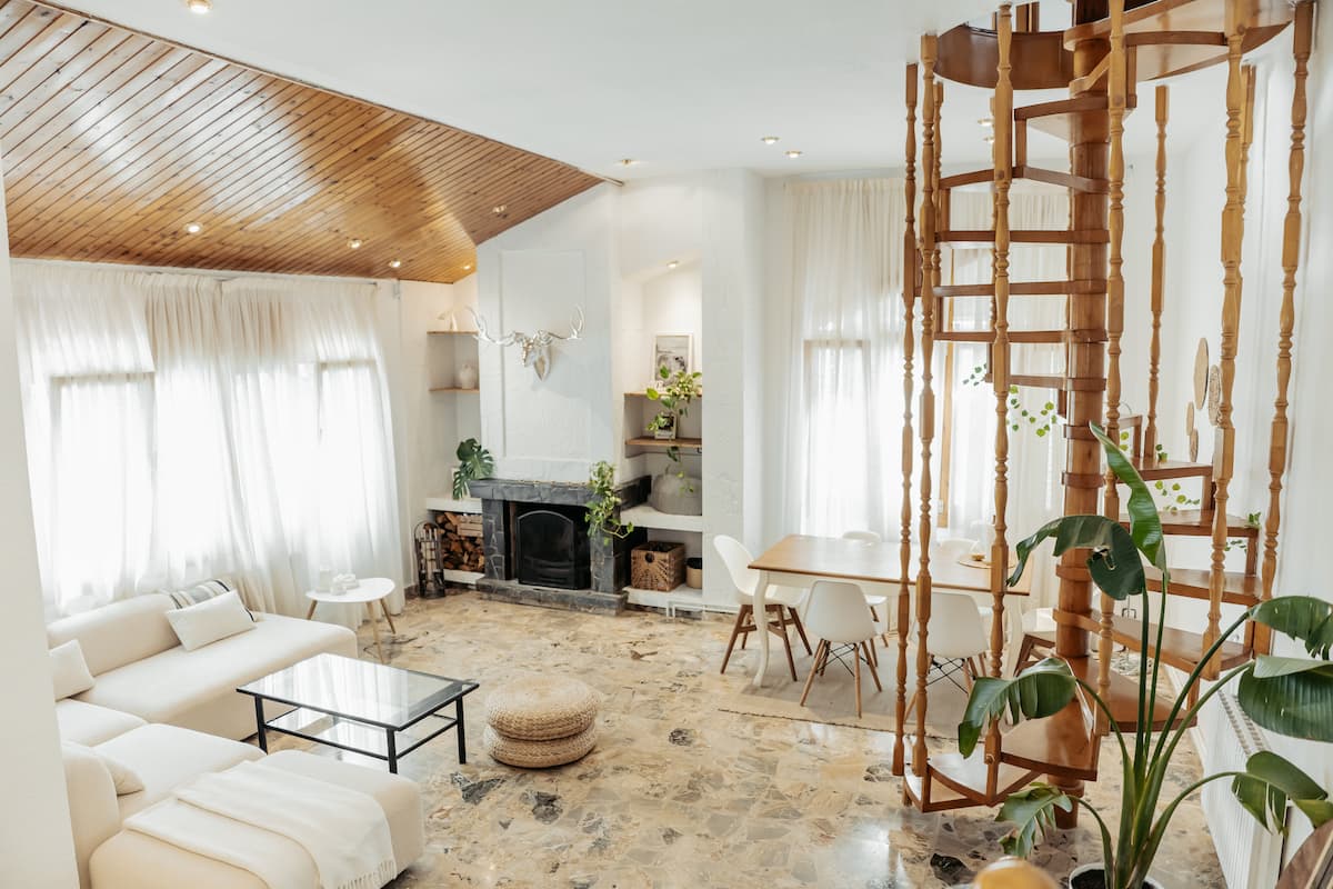 The open-plan living room with fireplace, timber ceiling and spiral staircase