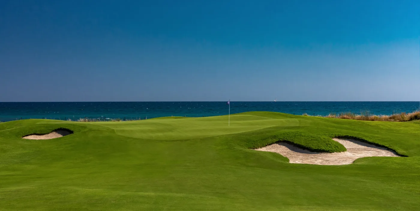 A green at Club de Golf Terramar with bunkers and the Mediterranean directly behind it