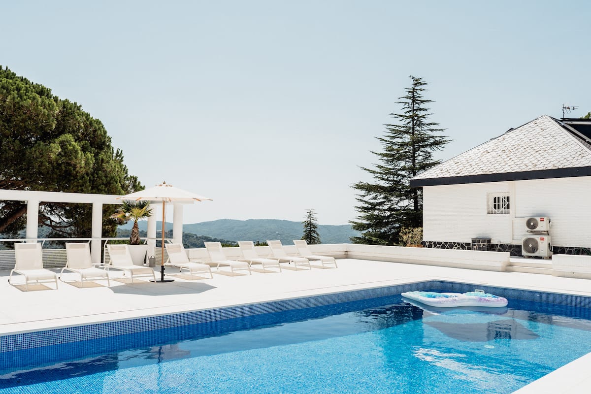 Sun loungers and a parasol beside the pool, looking out over the wooded hills