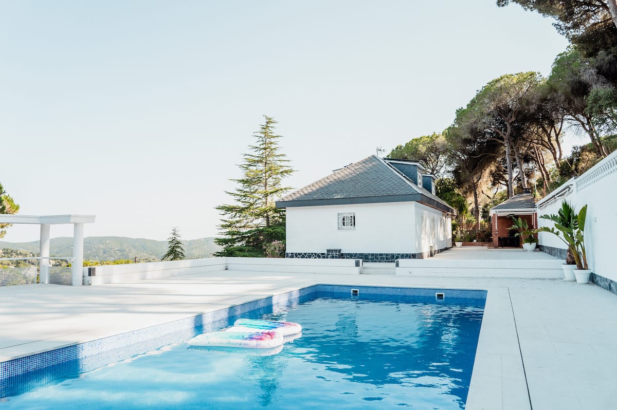 The saltwater pool at Casa Blanca with the white house and pine woods behind it